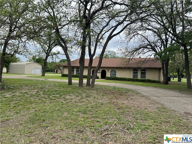 single story home featuring a front yard and an outbuilding