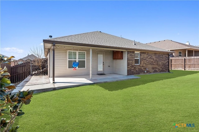 back of property with a yard, brick siding, a patio area, and a fenced backyard