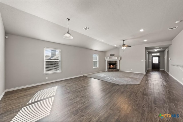 unfurnished living room featuring a brick fireplace, baseboards, visible vents, and wood finished floors