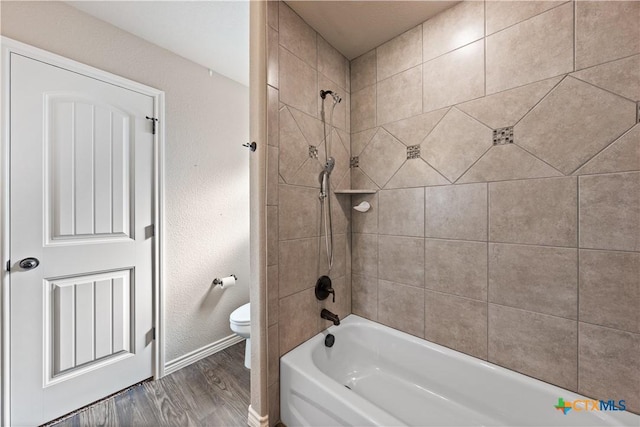 bathroom featuring bathtub / shower combination, wood finished floors, toilet, and baseboards