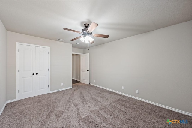 unfurnished bedroom with ceiling fan, visible vents, baseboards, a closet, and carpet