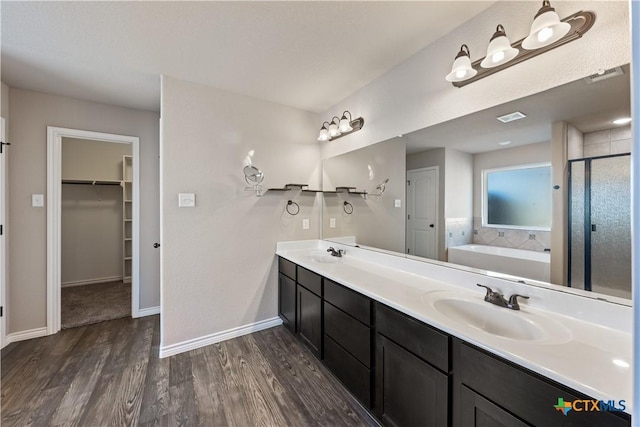 full bathroom featuring wood finished floors, a stall shower, a sink, and visible vents