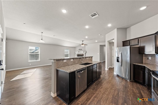 kitchen featuring visible vents, dark wood finished floors, appliances with stainless steel finishes, a sink, and backsplash