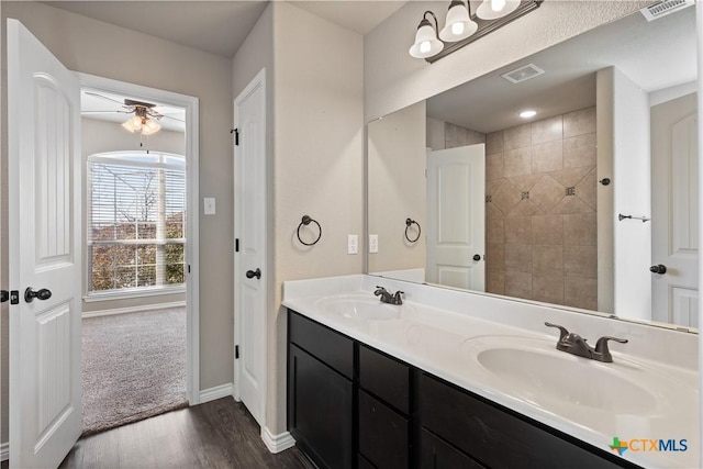 full bathroom featuring double vanity, visible vents, a sink, and wood finished floors