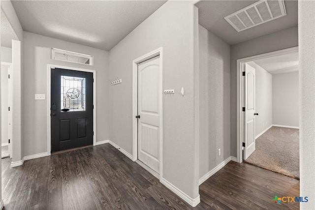 foyer entrance featuring visible vents, dark wood finished floors, and baseboards