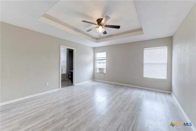 spare room with light hardwood / wood-style floors, ceiling fan, and a tray ceiling