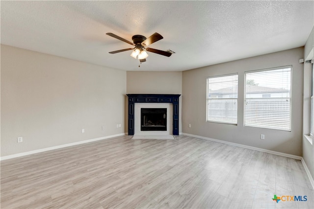 unfurnished living room featuring hardwood / wood-style floors, ceiling fan, and a textured ceiling