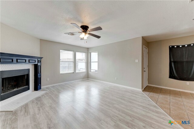 unfurnished living room with a textured ceiling, ceiling fan, and light hardwood / wood-style flooring