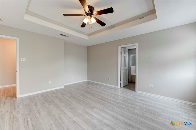 empty room with light hardwood / wood-style floors, ceiling fan, and a raised ceiling