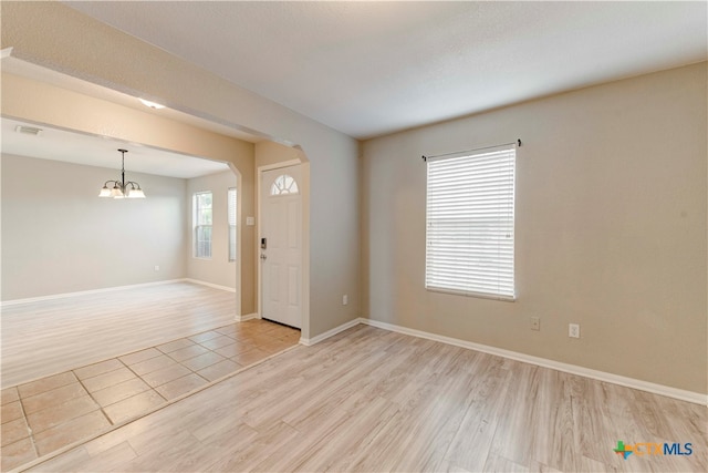 unfurnished room with a chandelier and light hardwood / wood-style flooring