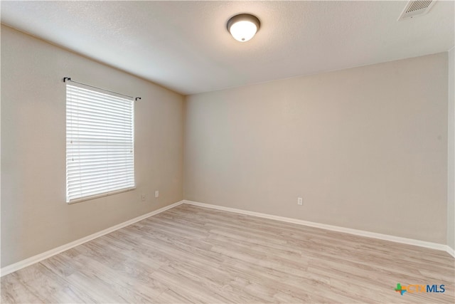 spare room featuring light wood-type flooring and a textured ceiling