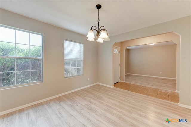 empty room with hardwood / wood-style floors and a notable chandelier