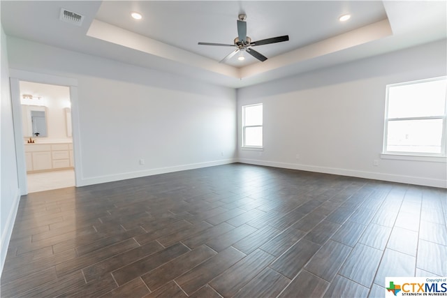 unfurnished room featuring ceiling fan, a healthy amount of sunlight, and a raised ceiling