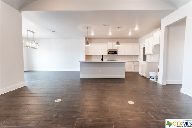 kitchen featuring sink, hanging light fixtures, a kitchen island with sink, white cabinets, and decorative backsplash