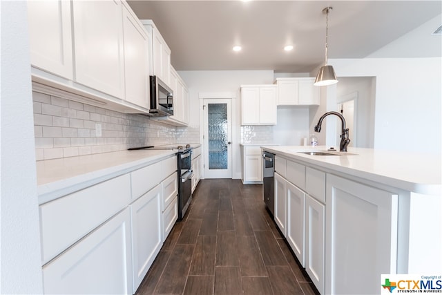 kitchen with stainless steel appliances, white cabinetry, dark hardwood / wood-style floors, pendant lighting, and sink