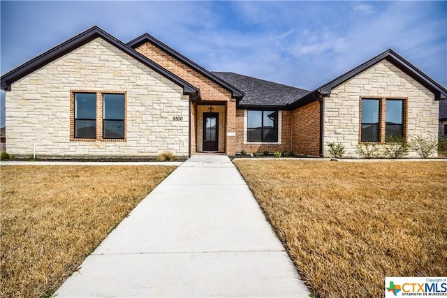 8500 Kasen Ave, Killeen, TX 76542 - view of front of home featuring stone siding, a front yard, and roof with shingles