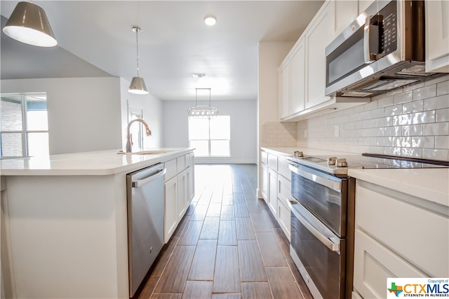 kitchen with a wealth of natural light, sink, an island with sink, and stainless steel appliances