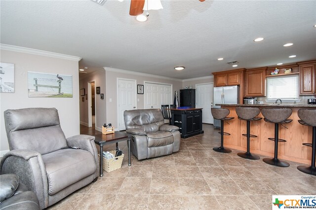 living room with light tile patterned flooring, sink, ceiling fan, and crown molding