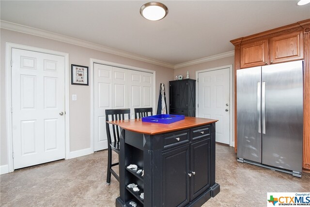 kitchen with a kitchen island, stainless steel refrigerator, crown molding, and a breakfast bar area