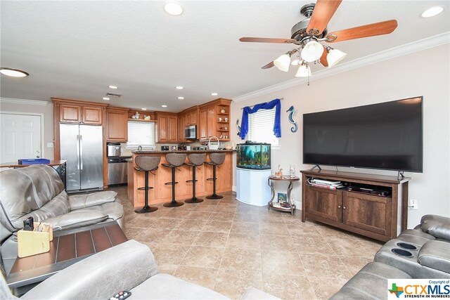 tiled living room with ornamental molding and ceiling fan