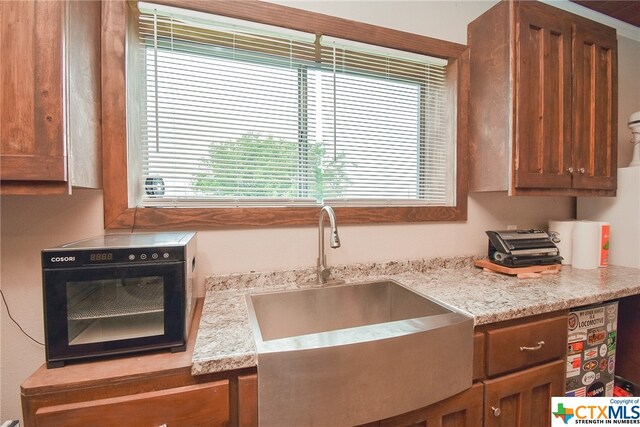 kitchen featuring sink, light stone counters, and plenty of natural light