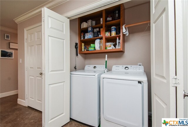 laundry area featuring dark tile patterned flooring, washer and dryer, and ornamental molding