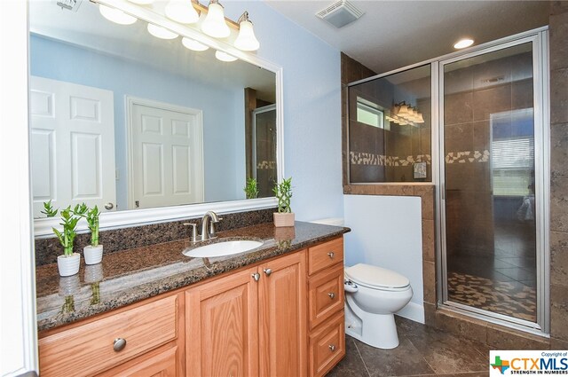 bathroom with tile patterned floors, vanity, toilet, and an enclosed shower