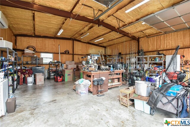 garage featuring wood walls, a workshop area, and a wall mounted air conditioner