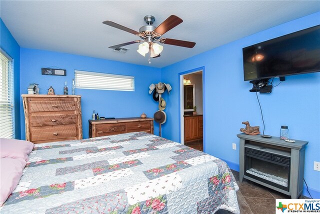 tiled bedroom with connected bathroom and ceiling fan