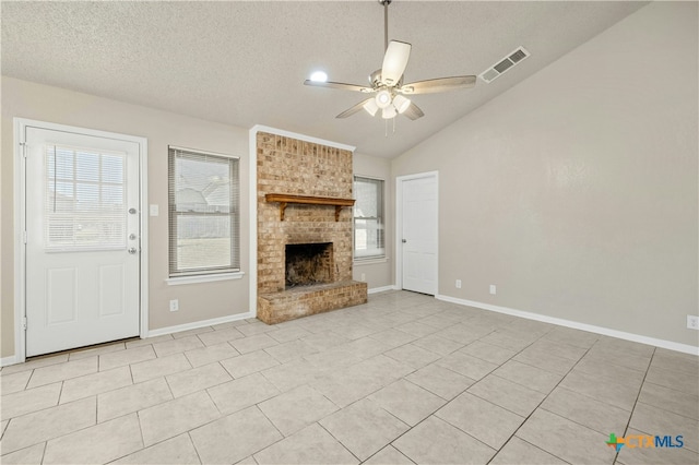 unfurnished living room with a healthy amount of sunlight, a brick fireplace, visible vents, and lofted ceiling