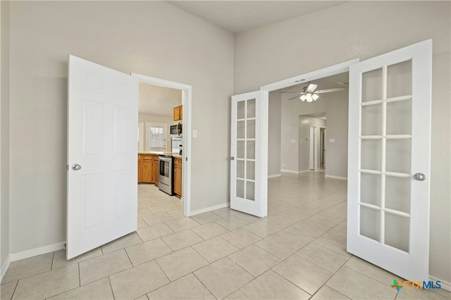 spare room featuring a ceiling fan, french doors, baseboards, and light tile patterned floors