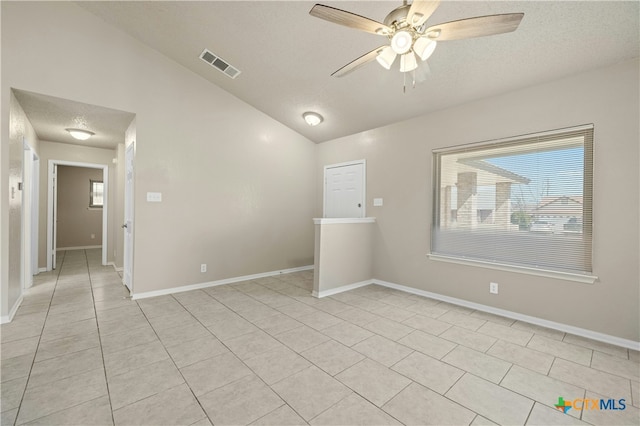 empty room with baseboards, visible vents, ceiling fan, vaulted ceiling, and a textured ceiling