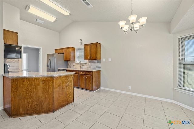 kitchen with lofted ceiling, a sink, visible vents, stainless steel refrigerator with ice dispenser, and brown cabinets