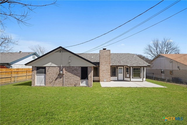 back of house with a fenced backyard, a chimney, a lawn, and a patio