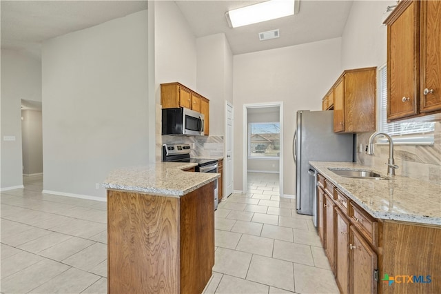 kitchen featuring visible vents, brown cabinetry, appliances with stainless steel finishes, a sink, and light tile patterned flooring