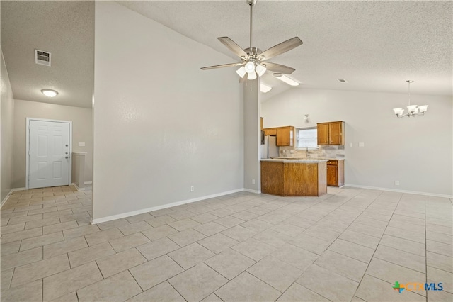 unfurnished living room with visible vents, ceiling fan with notable chandelier, vaulted ceiling, a textured ceiling, and light tile patterned flooring