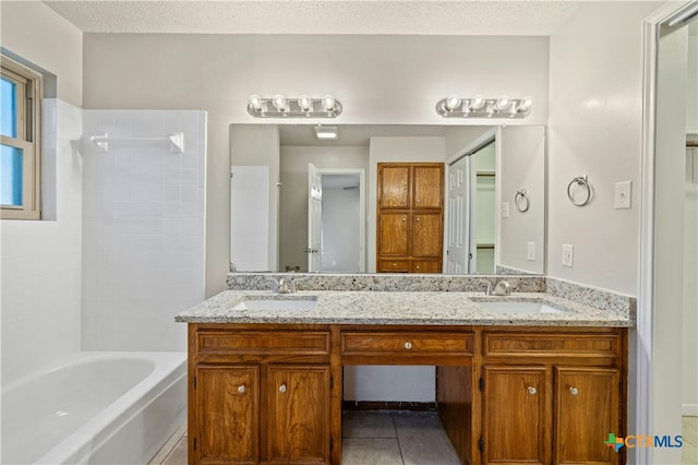 full bathroom featuring a textured ceiling, tile patterned flooring, and a sink