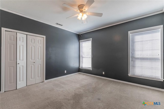 unfurnished bedroom with carpet, visible vents, baseboards, a closet, and crown molding