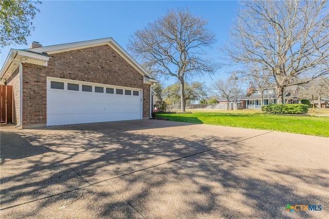 view of home's exterior with fence, driveway, a chimney, a lawn, and brick siding