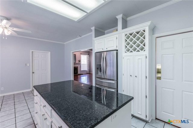 kitchen featuring ornamental molding, light tile patterned floors, a fireplace, stainless steel refrigerator with ice dispenser, and white cabinets