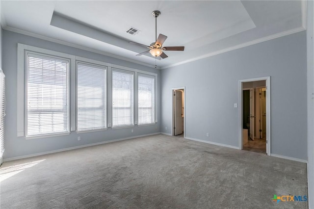 interior space with visible vents, ornamental molding, baseboards, carpet floors, and a raised ceiling