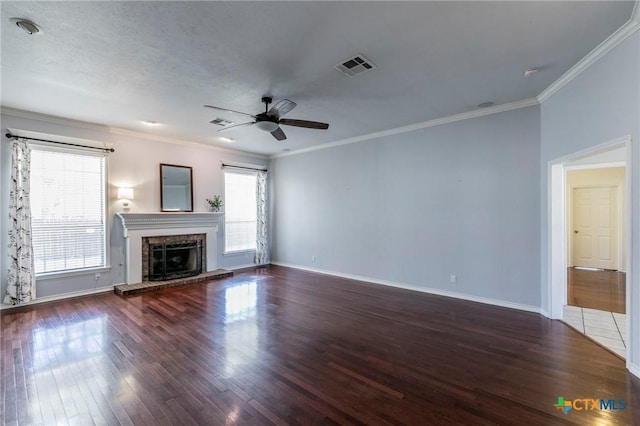 unfurnished living room featuring visible vents, a fireplace with raised hearth, ornamental molding, wood finished floors, and a ceiling fan