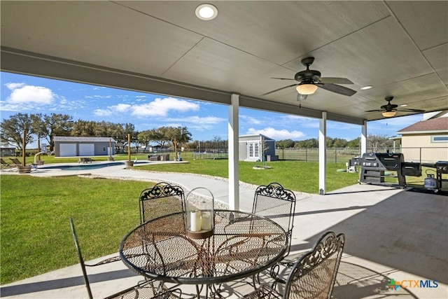 view of patio / terrace featuring outdoor dining space, a shed, fence, an outdoor structure, and ceiling fan