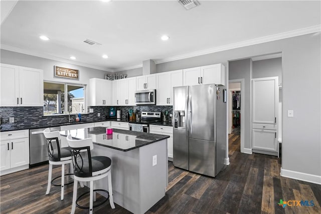 kitchen with dark countertops, visible vents, appliances with stainless steel finishes, and a center island