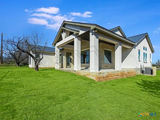 back of property with central AC unit and a yard