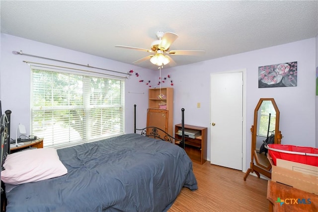 bedroom featuring ceiling fan, hardwood / wood-style floors, and a textured ceiling