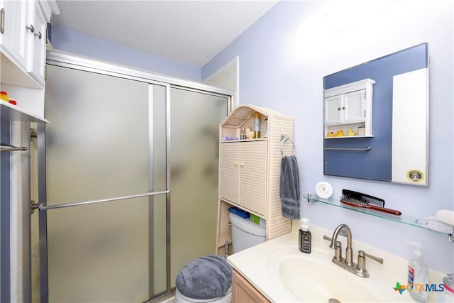 bathroom with toilet, a shower with door, and a textured ceiling