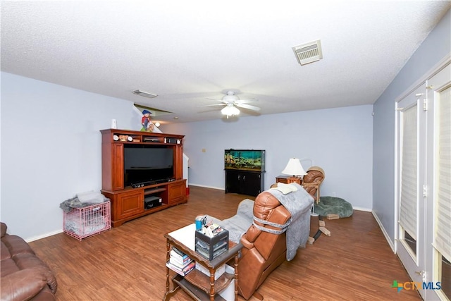 living room with wood-type flooring, a textured ceiling, and ceiling fan