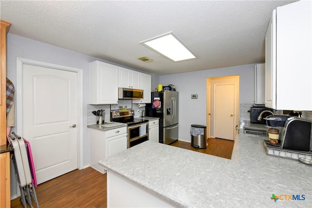 kitchen with stainless steel appliances, kitchen peninsula, white cabinets, and decorative backsplash