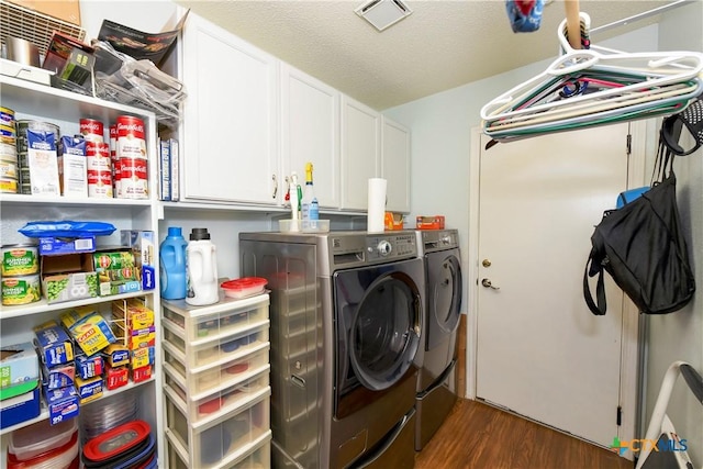 clothes washing area featuring dark hardwood / wood-style flooring, cabinets, independent washer and dryer, and a textured ceiling